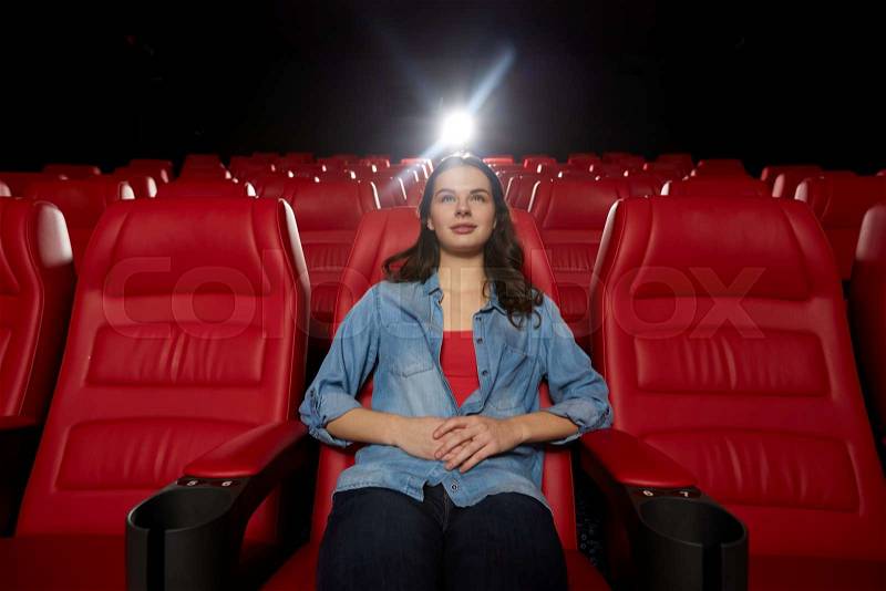 Cinema, entertainment and people concept - young woman watching movie alone in empty theater auditorium, stock photo