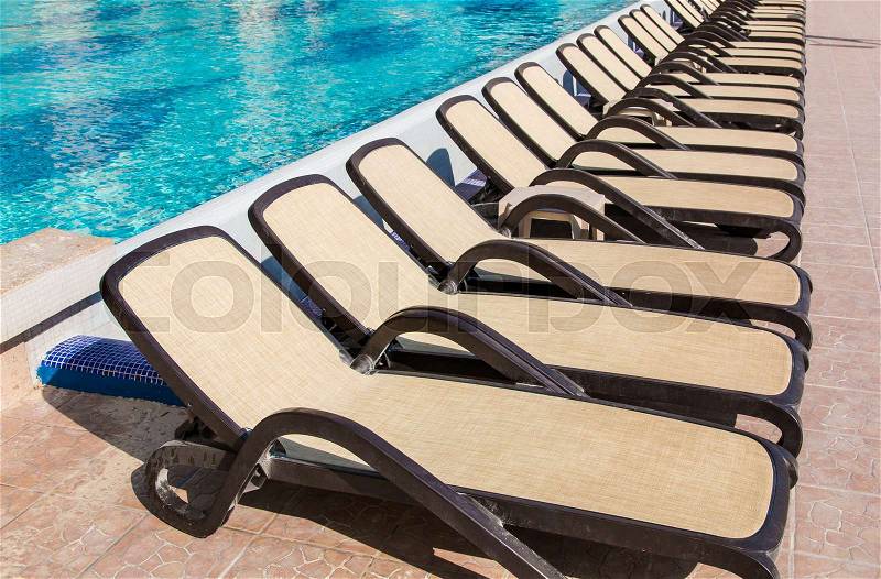 Line of empty chaise-longue near swimming pool, stock photo