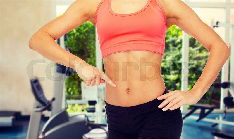 Fitness, exercise and diet concept - close up of woman pointing finger at her six pack, stock photo