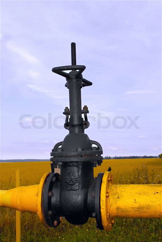 Valve on the gas pipe on the background of blue sky and field, stock photo