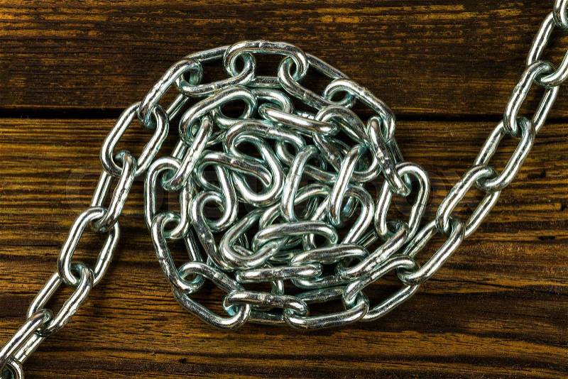 Links of the steel chromeplated chain on wooden background, stock photo