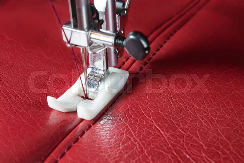 Sewing machine and red leather with a seam close-up, stock photo