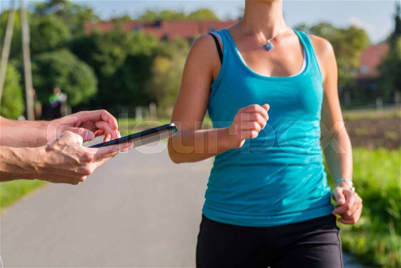 Woman doing jogging or outdoor running sport for fitness on rural street, the trainer stopping her time with app on tablet computer, stock photo