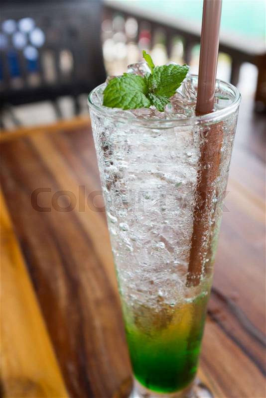Mint soda fresh cold drink soda water ice cubes in glass peppermint on topping on wood table in restaurant, stock photo