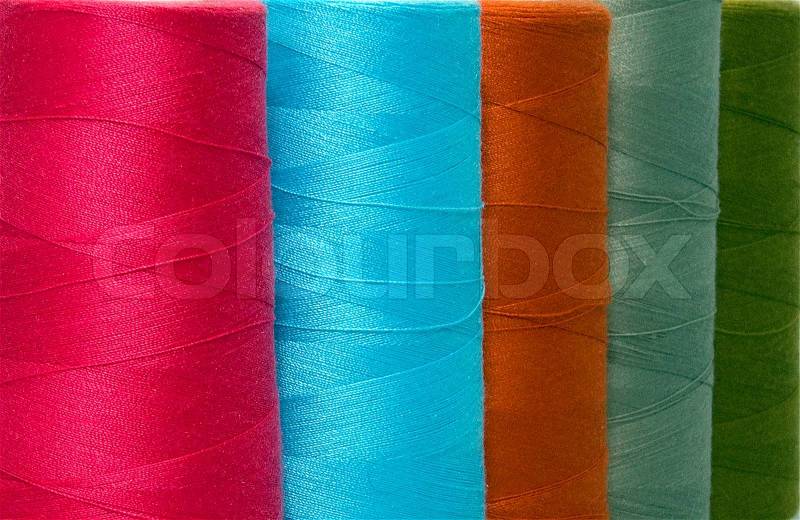 Different colors of sewing cotton used in textile and fashion industry, stock photo