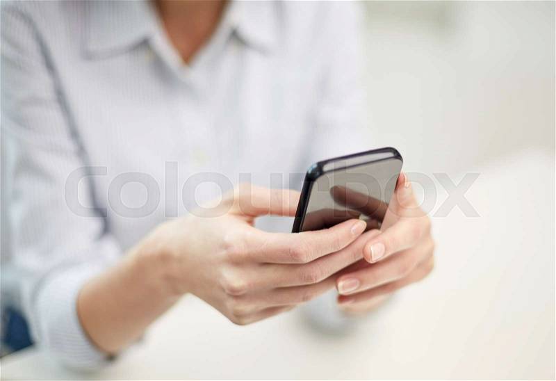 Business, technology and people concept - close up of woman hands texting message on smartphone at office, stock photo