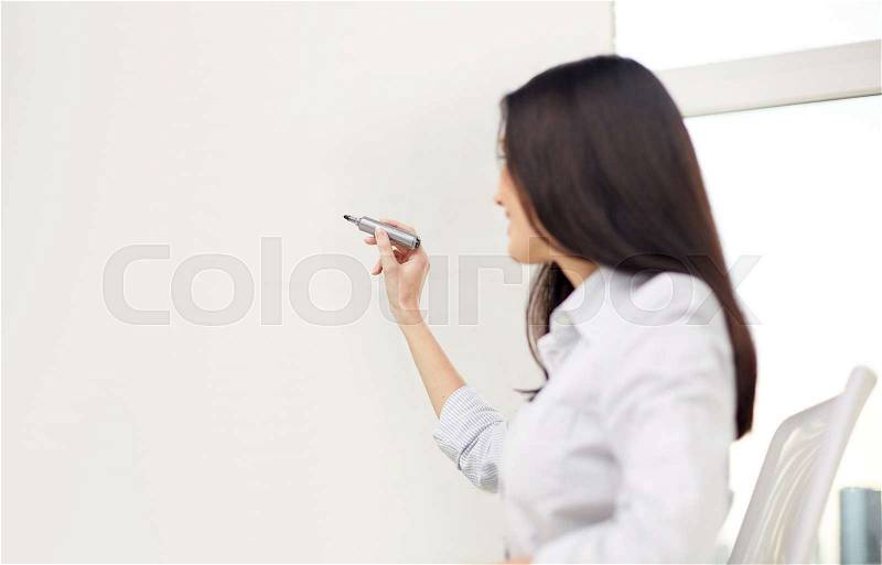 Education, business and people concept - happy woman with marker writing on whiteboard, stock photo
