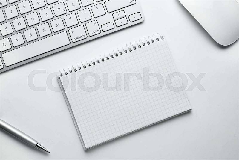 Conceptual White Ballpoint Pen, Clean Spiral Notes, Computer Keyboard and Mouse on Top of White Table with Copy Space at the Center, stock photo