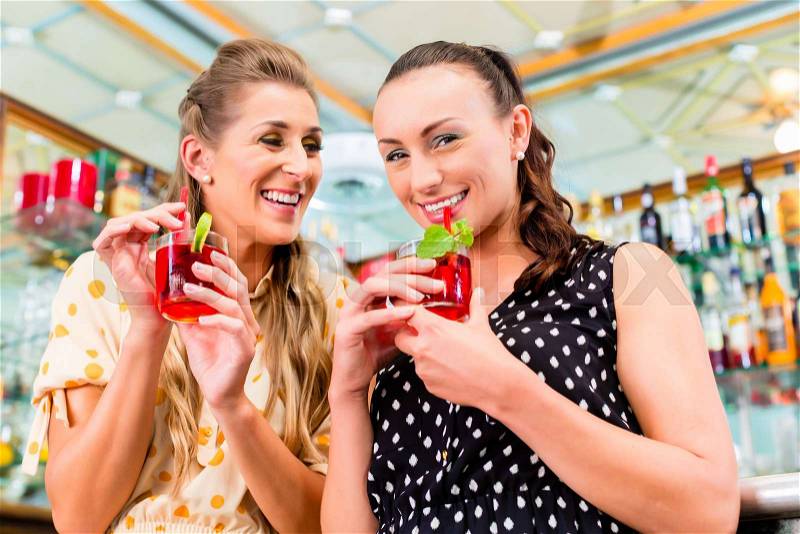 Two women friends in cafe bar drinking long drink or cocktails, stock photo