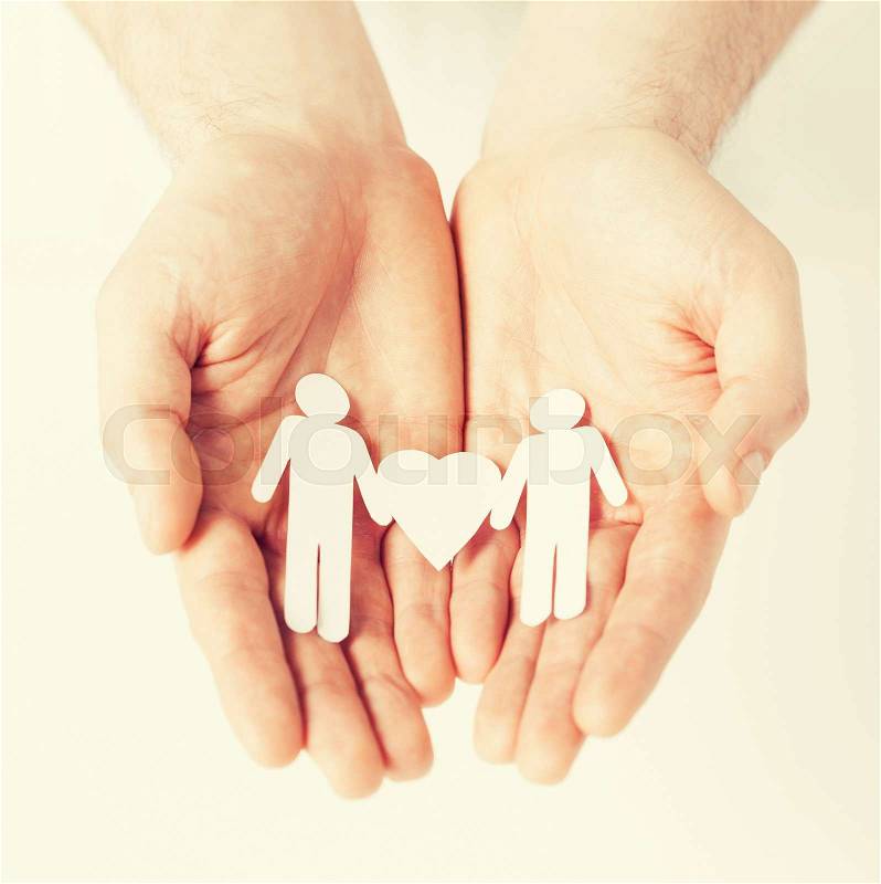 Mans hands showing two paper men with heart shape, stock photo