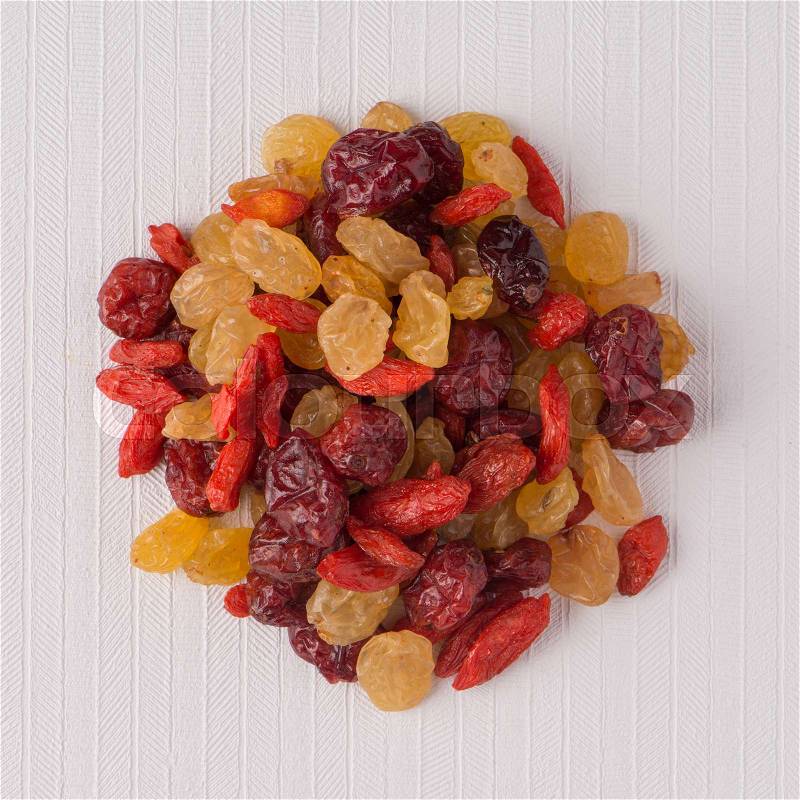 Top view of circle of mixed dried fruits against white vinyl background, stock photo