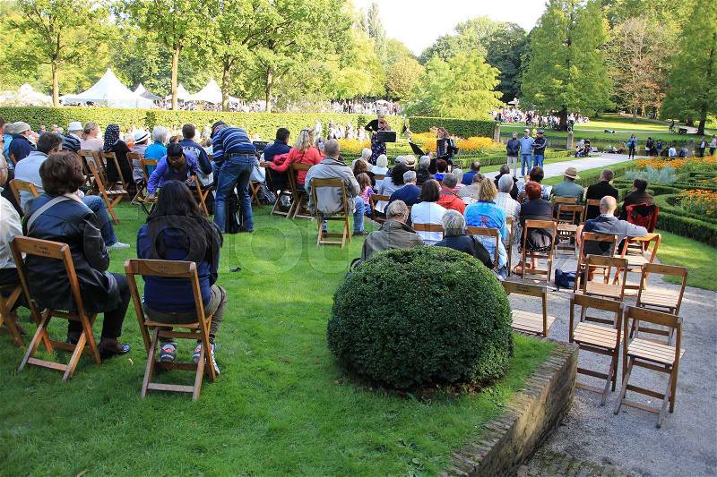 The audience listen attentive to the live show with the fiddler and piano accordionist in the open air in the summer in the Museum Park in Rotterdam in Holland, stock photo
