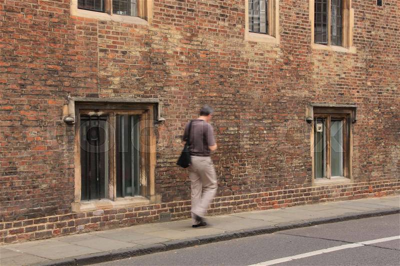 Man in brown shirt walks in the street in Cambridge in England in the summer, stock photo