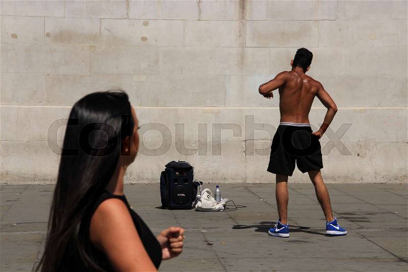 The lady in black looks interesting to the performer on the square in London in England in the summer, stock photo