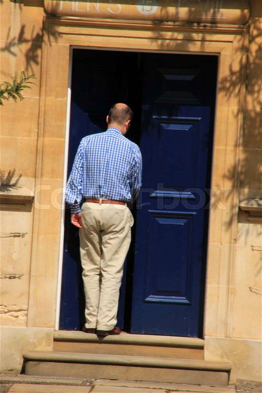 The teacher opens the door and goes inside the University in the summer in Oxford in England, stock photo
