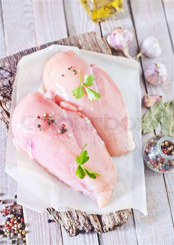 Raw chicken fillet on board and on a table, stock photo