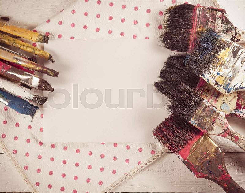 Set of used paint bruches with paper on wood background,vintage color toned image, stock photo