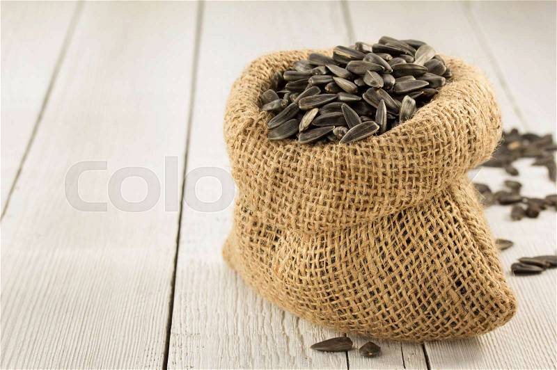 Sunflower seeds in bag on wooden background, stock photo