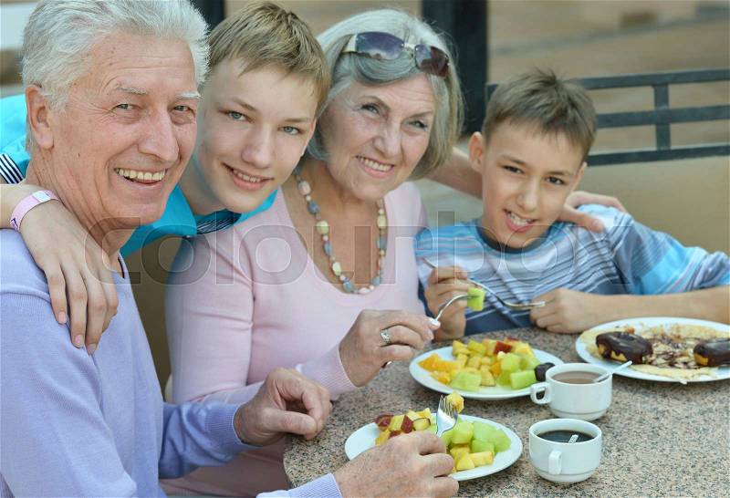 Grandparents with grandchildren at breakfast on tropical resort, stock photo
