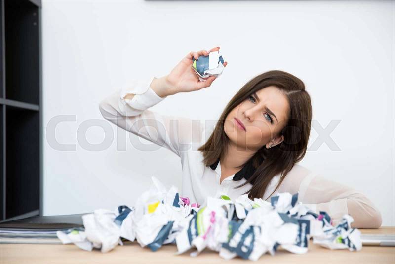 Businesswoman sitting at the table with trash paper, stock photo