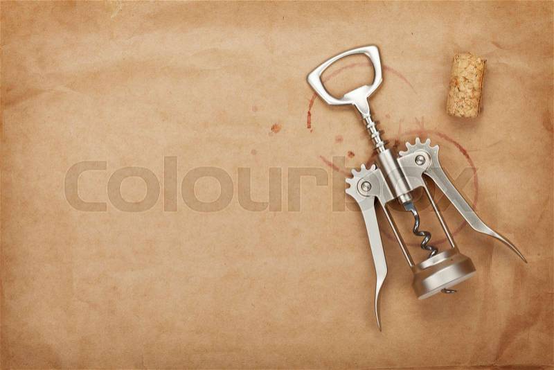 Cork and corkscrew with red wine stains on brown paper background with copy space, stock photo