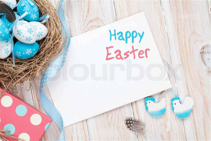 Easter greeting card with blue and white eggs and gift box over white wood. Top view with copy space, stock photo