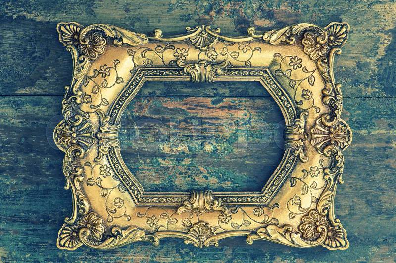 Vintage baroque golden frame on wooden background. Grunge wood texture. Retro style toned picture, stock photo