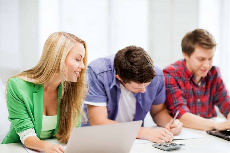 Education and internet - smiling students writing test or exam in lecture at school, stock photo