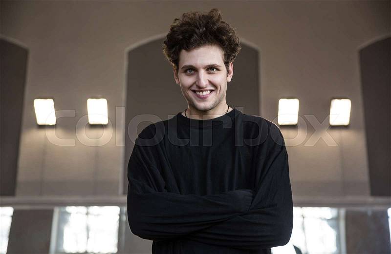 Portrait of a smiling young man with arms folded, stock photo