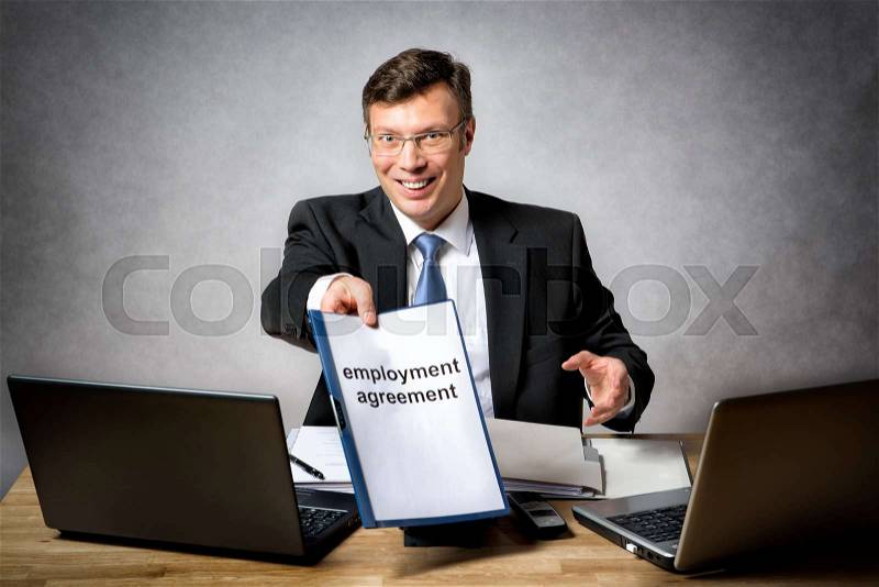 Boss sitting at the desk in office gives somebody a employment agreement, stock photo