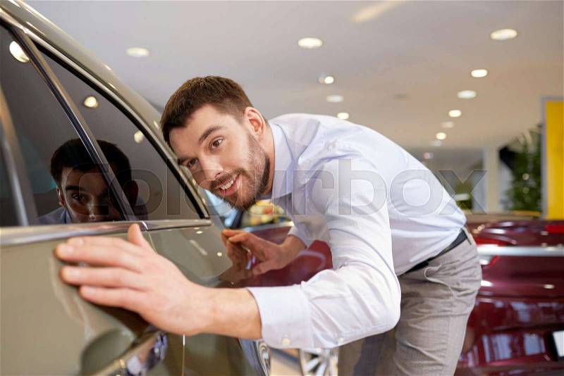 Auto business, car sale, consumerism and people concept - happy man touching car in auto show or salon, stock photo