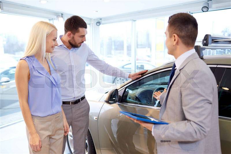 Auto business, car sale, technology and people concept - happy couple with car dealer in auto show or salon, stock photo