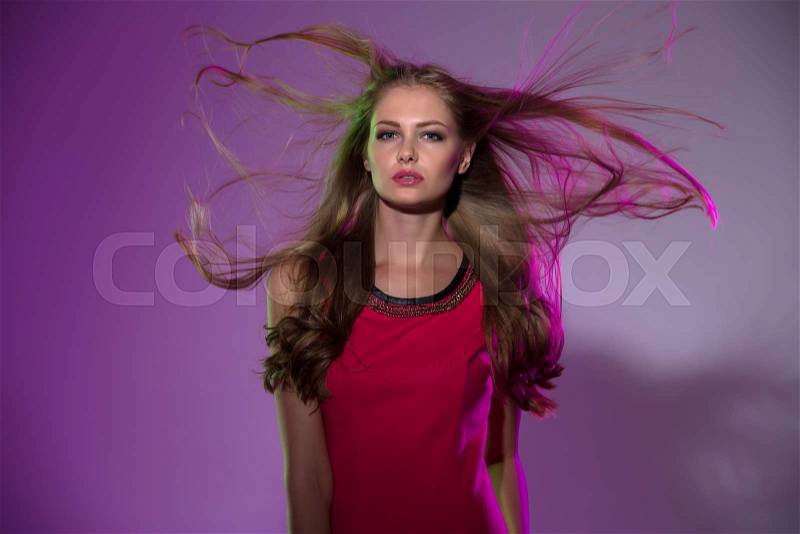 Studio portrait of long-haired girl in bright pink background with flying hair in the wind, stock photo