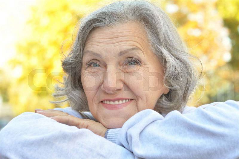 Portrait of a happy happy senior woman in autumn park, stock photo