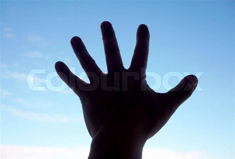 Silhouette of human hand on sky background, stock photo