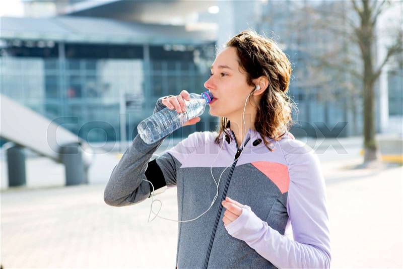 View of a Woman drinking water during a running session, stock photo