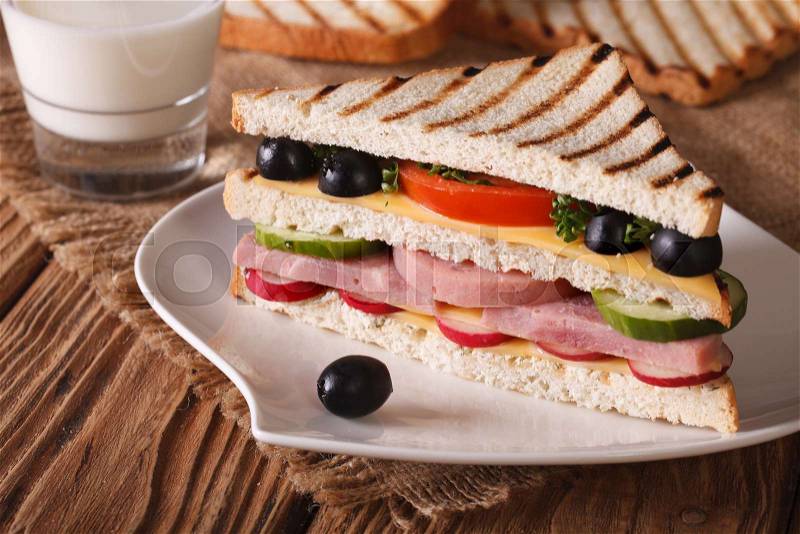 Sandwich with ham and vegetables on the plate and milk on the table. horizontal , stock photo