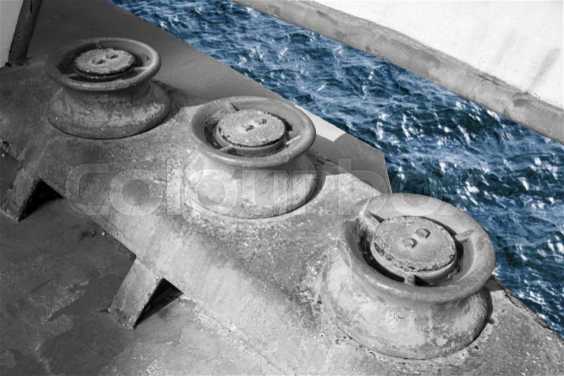 Old grungy rollers for mooring ropes, industrial ship monochrome fragment with blue sea water, stock photo
