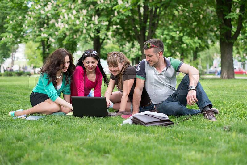 Group of Teenage Students at Park with Computer and Books, stock photo