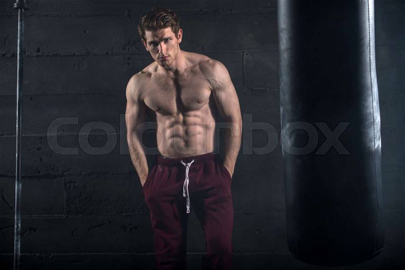 Athletic man with naked torso near concrete wall in the studio, stock photo