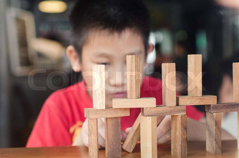 Asian boy playing with the wood game (jenga). Selective focus, stock photo