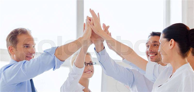 Success and winning concept - happy business team giving high five in office, stock photo