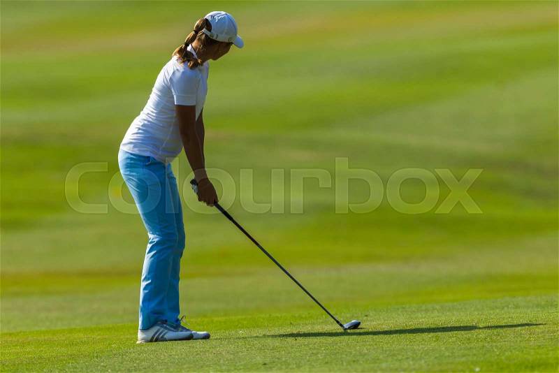 Golf girl on fairway with metal club setup to swing, stock photo