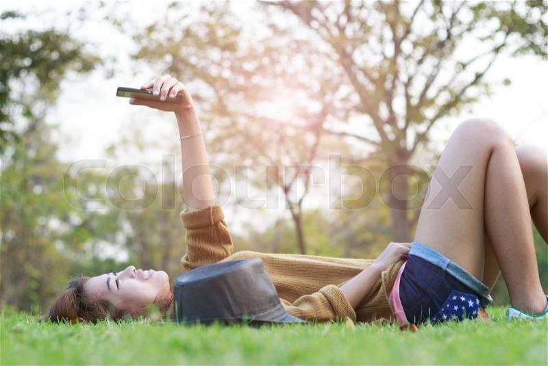 Young women smile use smart phone self picture selfie on green grass, stock photo