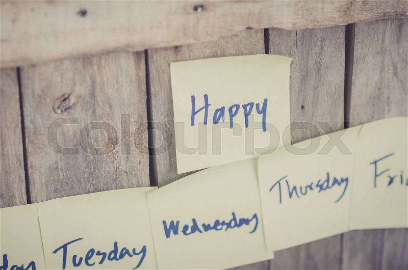 Vintage style effect Sunday Monday Tuesday Wednesday Thursday Friday and Saturday message on corkboard with flowers by wooden background, stock photo