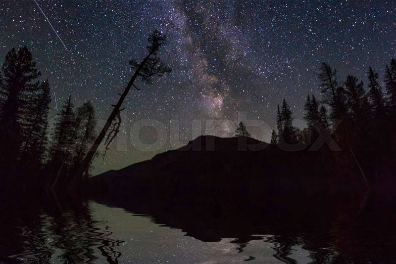 Amazing night landscape with mountains and stars. Reflection of the night sky in the lake, stock photo