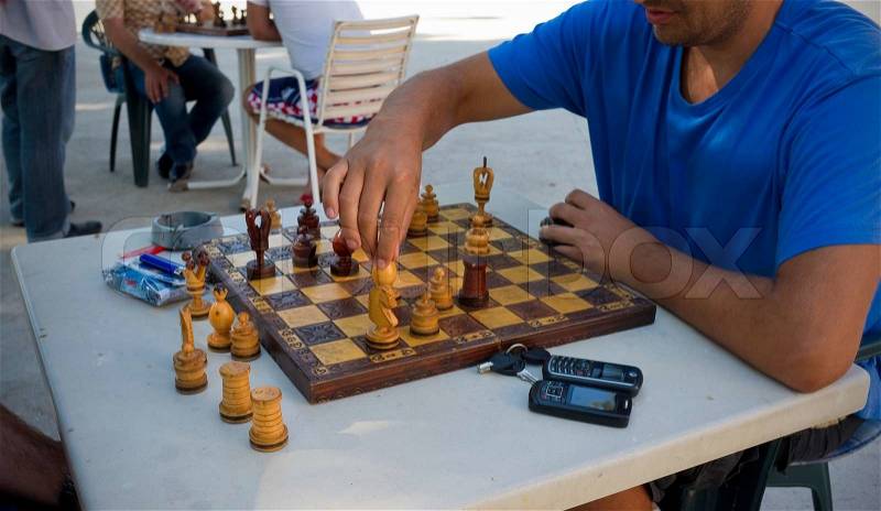 Croatian man taking a move in a chess match in the shade during the midday heat, stock photo