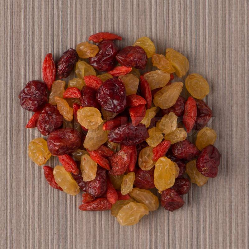 Top view of circle of mixed dried fruits against beige vinyl background, stock photo