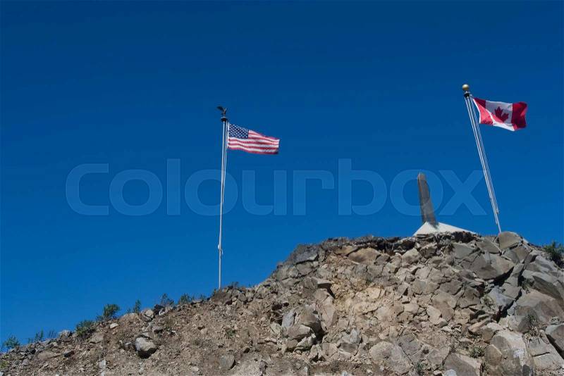 Flags flying at a US and Canadian border , stock photo