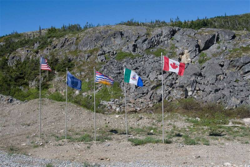Flags flying at a US and Canadian border , stock photo